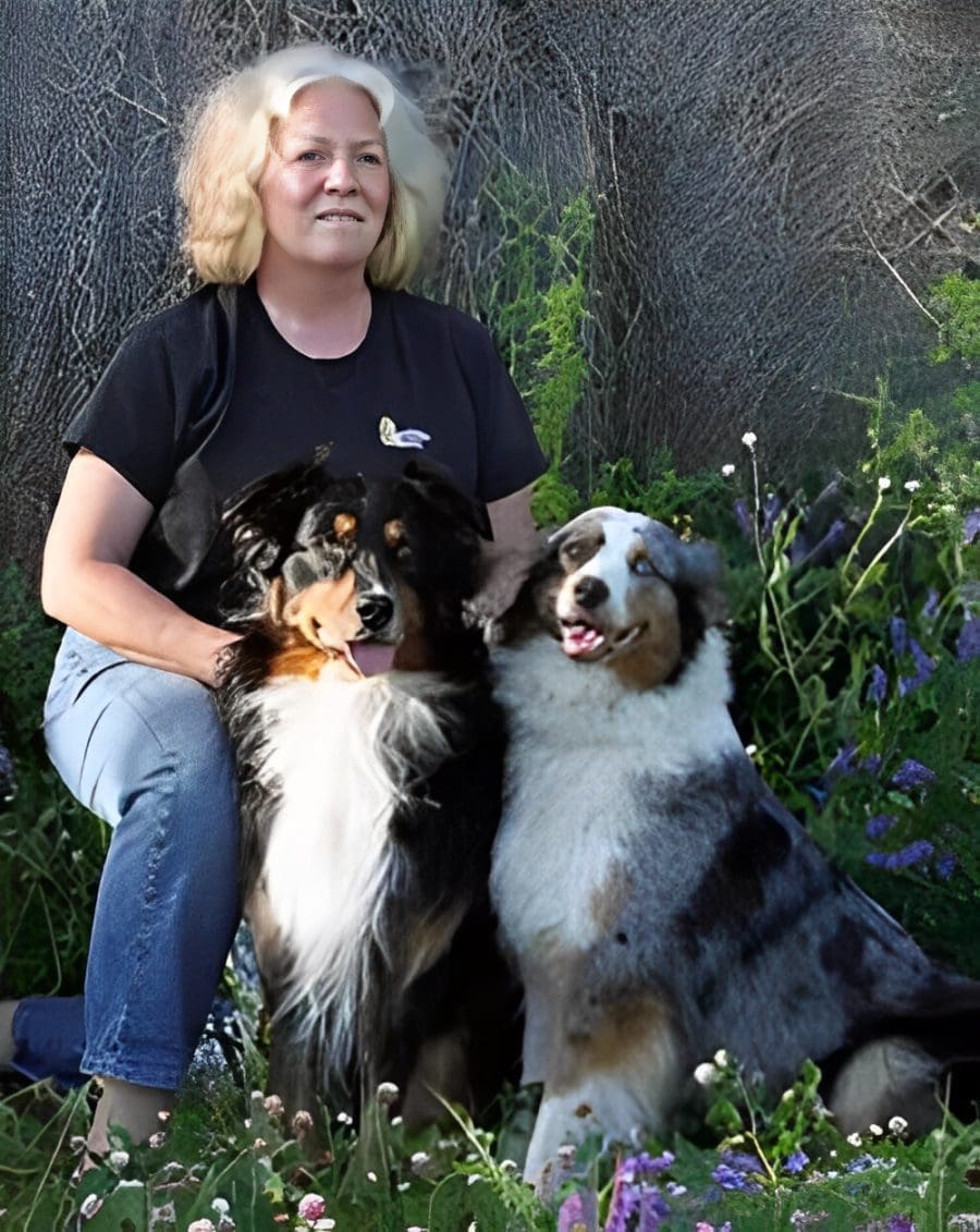 Smiling woman with two Australian Shepherds
